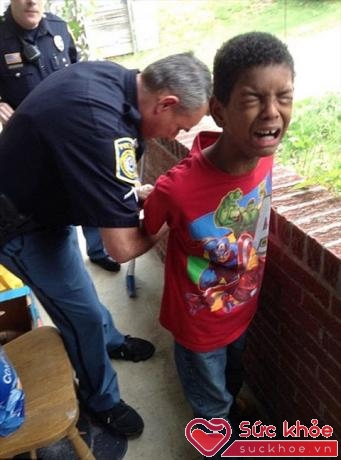 Cảnh sát còng tay và dẫn cậu bé 10 tuổi đi. Ảnh: ABC News