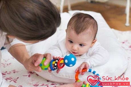 Đặt trẻ lên một chiếc gối dành cho trẻ sơ sinh cùng với một vài món đồ chơi có thể sẽ giúp trẻ thích thú với việc nằm sấp hơn (Ảnh minh họa)