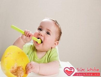 Khi 8 - 9 tháng, bé ngồi vững là có thể tập tự cầm thìa xúc ăn
