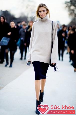 Người mẫu Anja Rubik ấn tượng trên phố với áo len cổ cao màu xám dáng rộng kết hợp cùng chân váy màu đen và bốt cao gót cổ thấp.